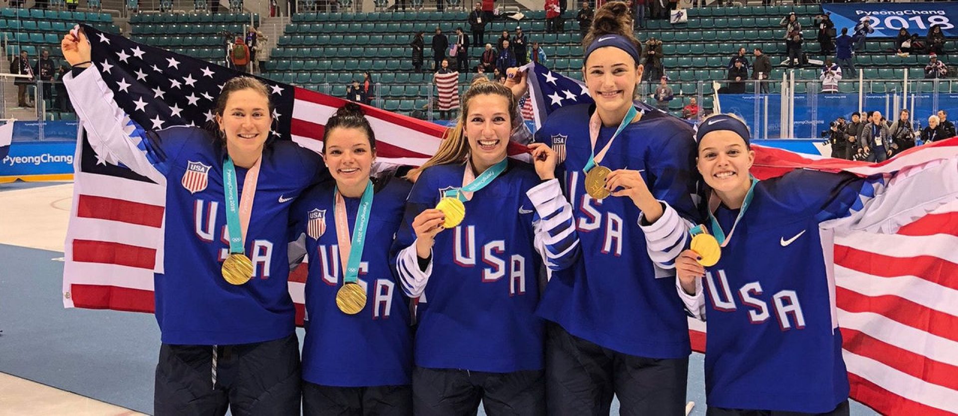 Women's hockey players holding an American flag