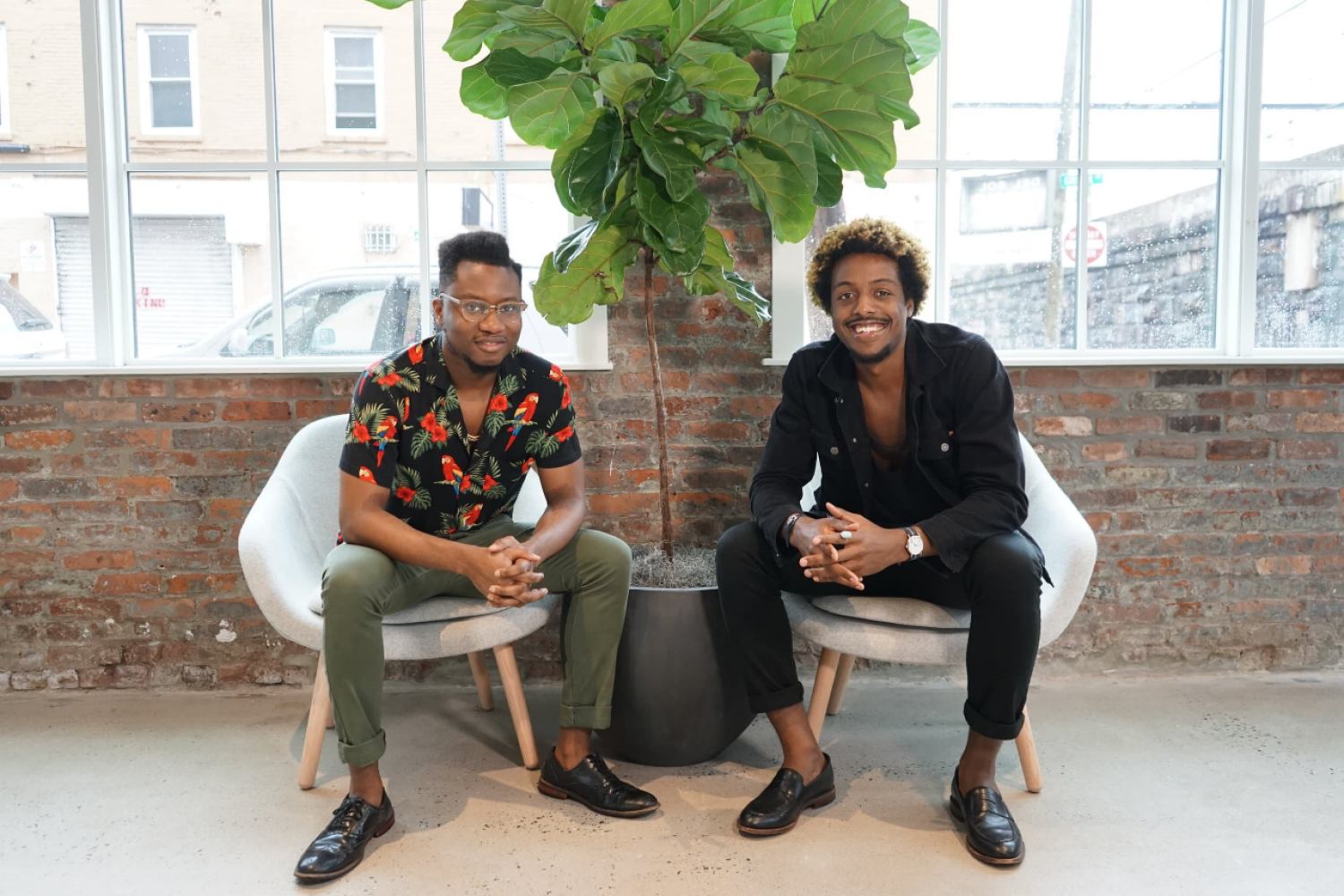 Ivan Alo and LaDante McMillon sitting in their office in front of a large plant
