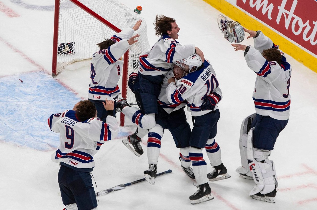 A group of US hockey players hug and celebrate on the ice