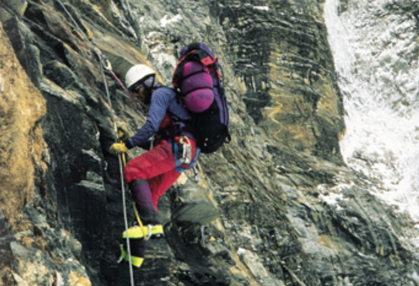Juan Montes climbing a mountain with gear strapped to his back