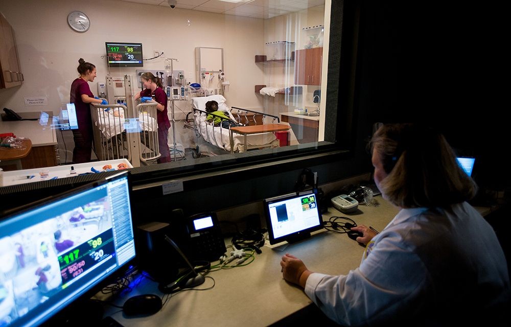 A group of nursing students standing over a hospital bed