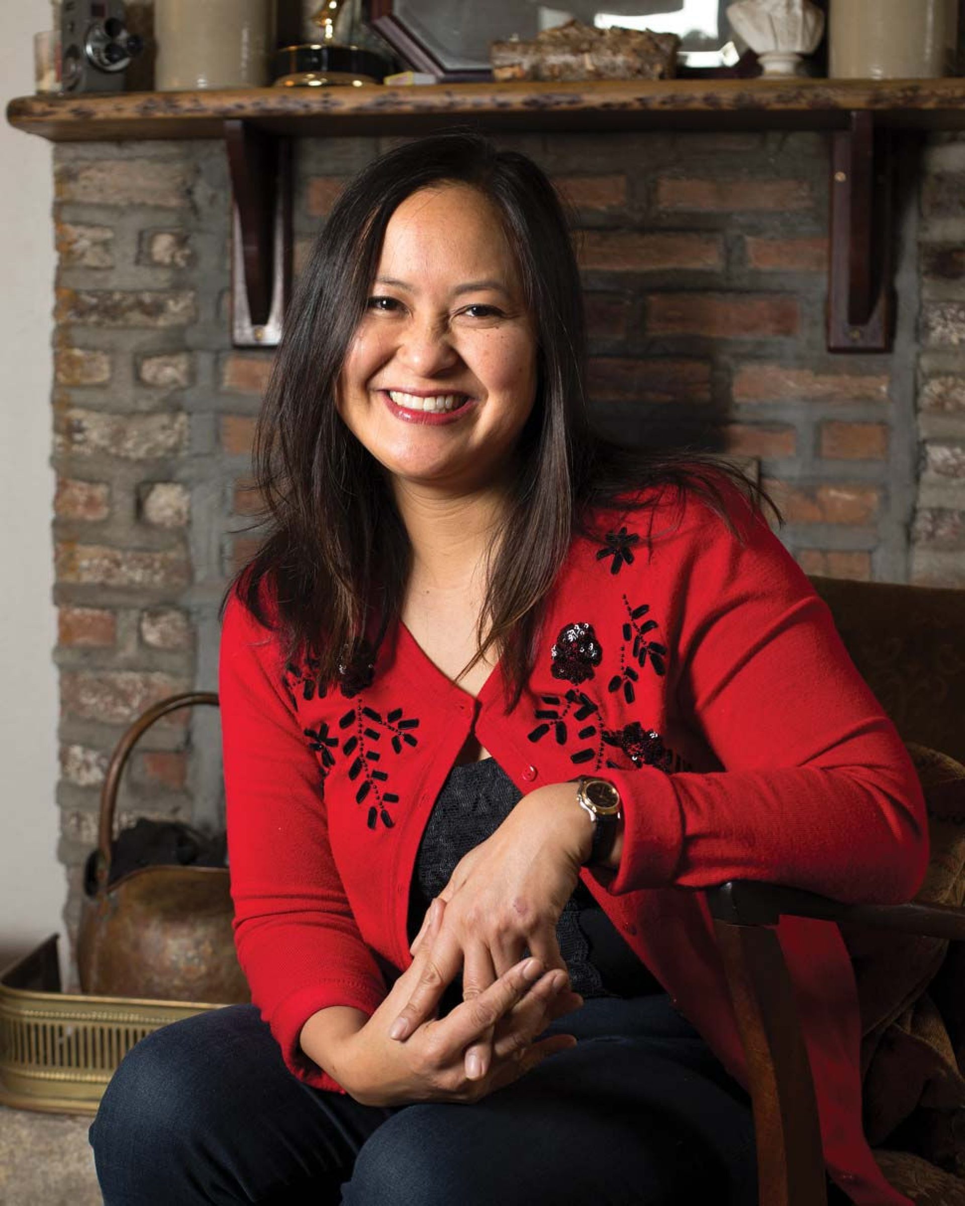 Photo of Marissa Aroy seated in front of a hearth