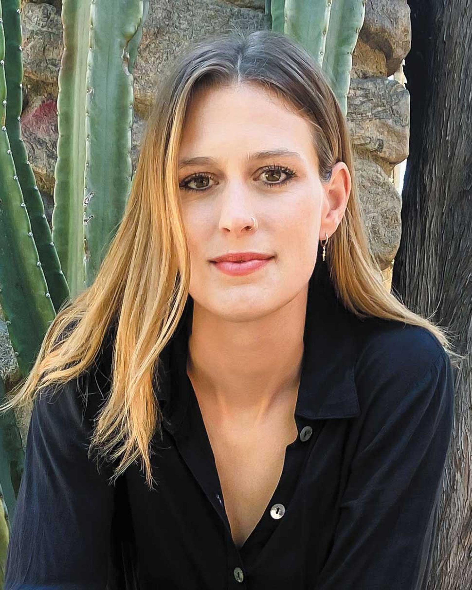 Elizabeth Flock photographed in front of cactus and stonewall.