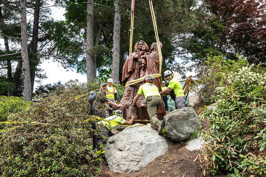 A crew lowers a statue onto a base